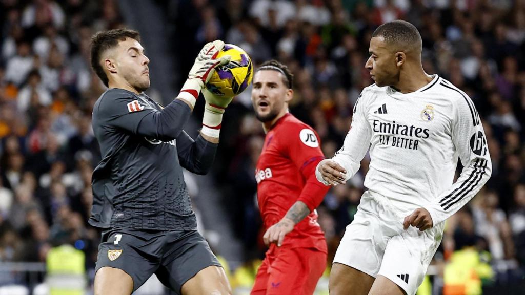 Álvaro Fernández bloca el balón ante la atenta mirada de Mbappé.