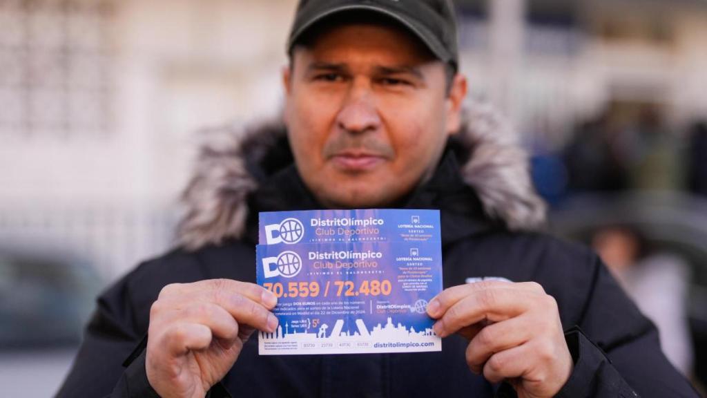 Un hombre sostiene un boleto del club de baloncesto Distrito Olímpico con el número del Gordo, el 72.480.