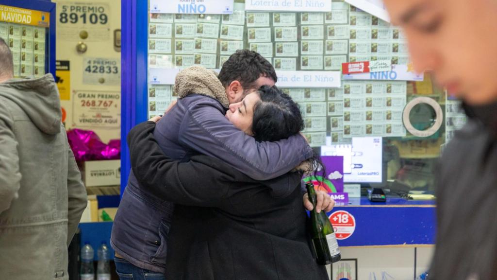 Dos personas se abrazan en la administración de loterías 'La Caprichosa' de Toledo tras el sorteo de 2023.