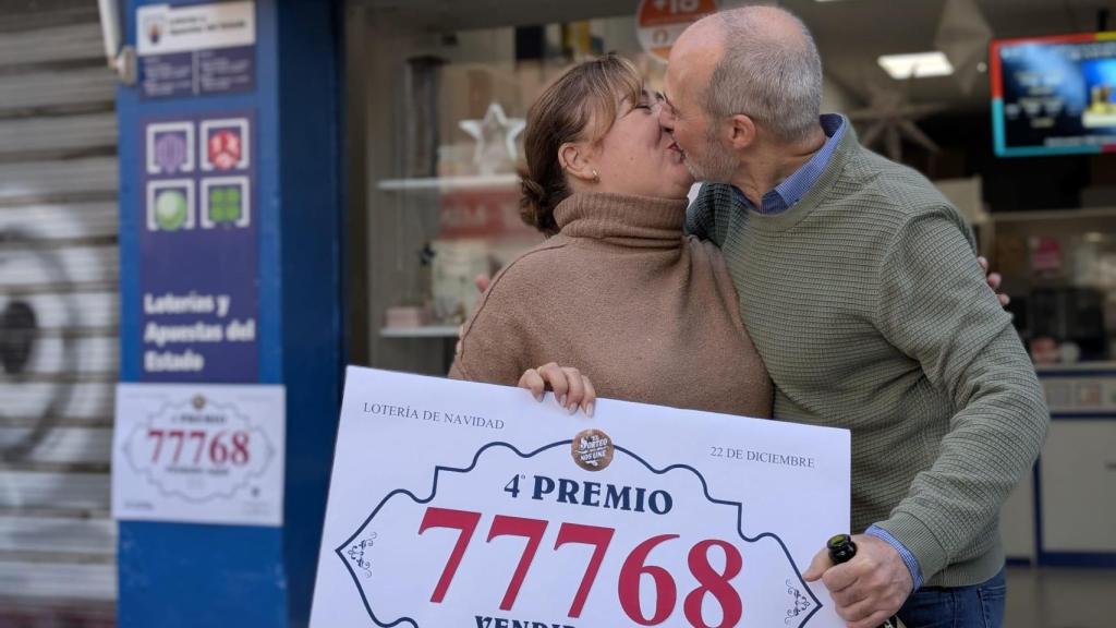 Ana Cuevas y su marido se dan un beso en la puerta de Baraka, donde han vendido un cuarto premio de la lotería de Navidad en Málaga.