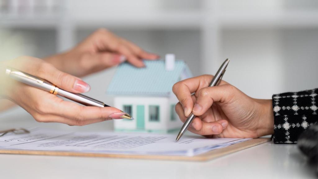 Fotografía de dos personas firmando un documento.