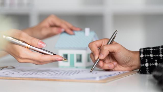 Fotografía de dos personas firmando un documento.