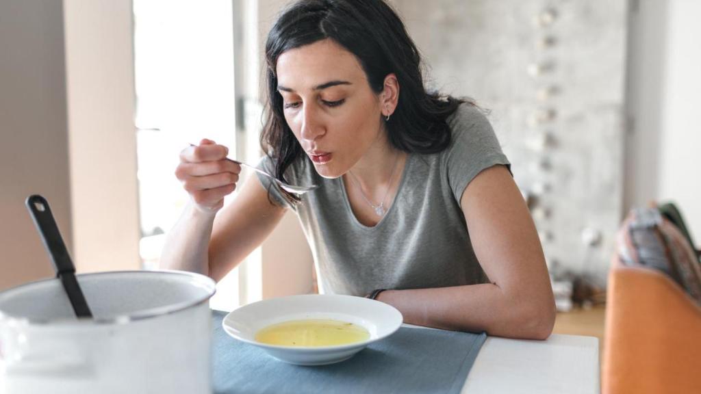 Mujer tomando sopa.