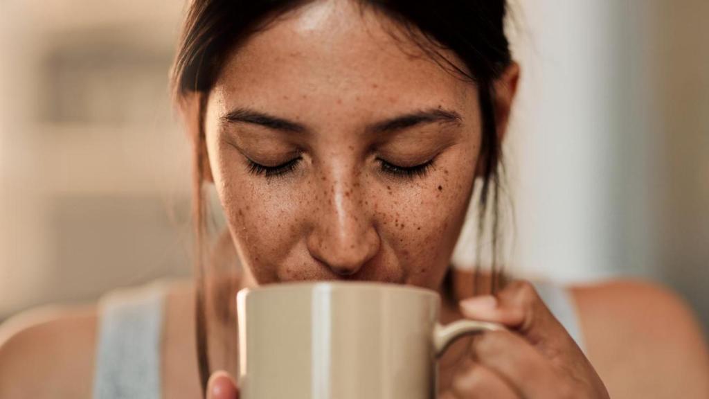 Mujer bebiendo de una taza caliente.