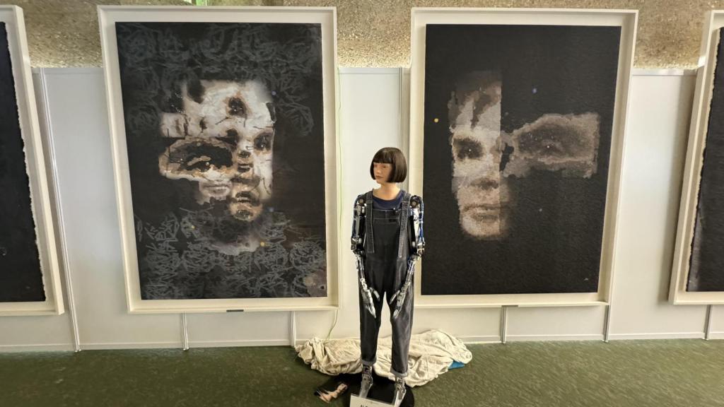 El robot artista Ai-Da, ante dos de sus cuadros. El de la derecha, 'A.I. God. Portrait of Alan Turing', se vendió por un millón de dólares en Sotheby's. Foto: Ai-Da Robot Studios