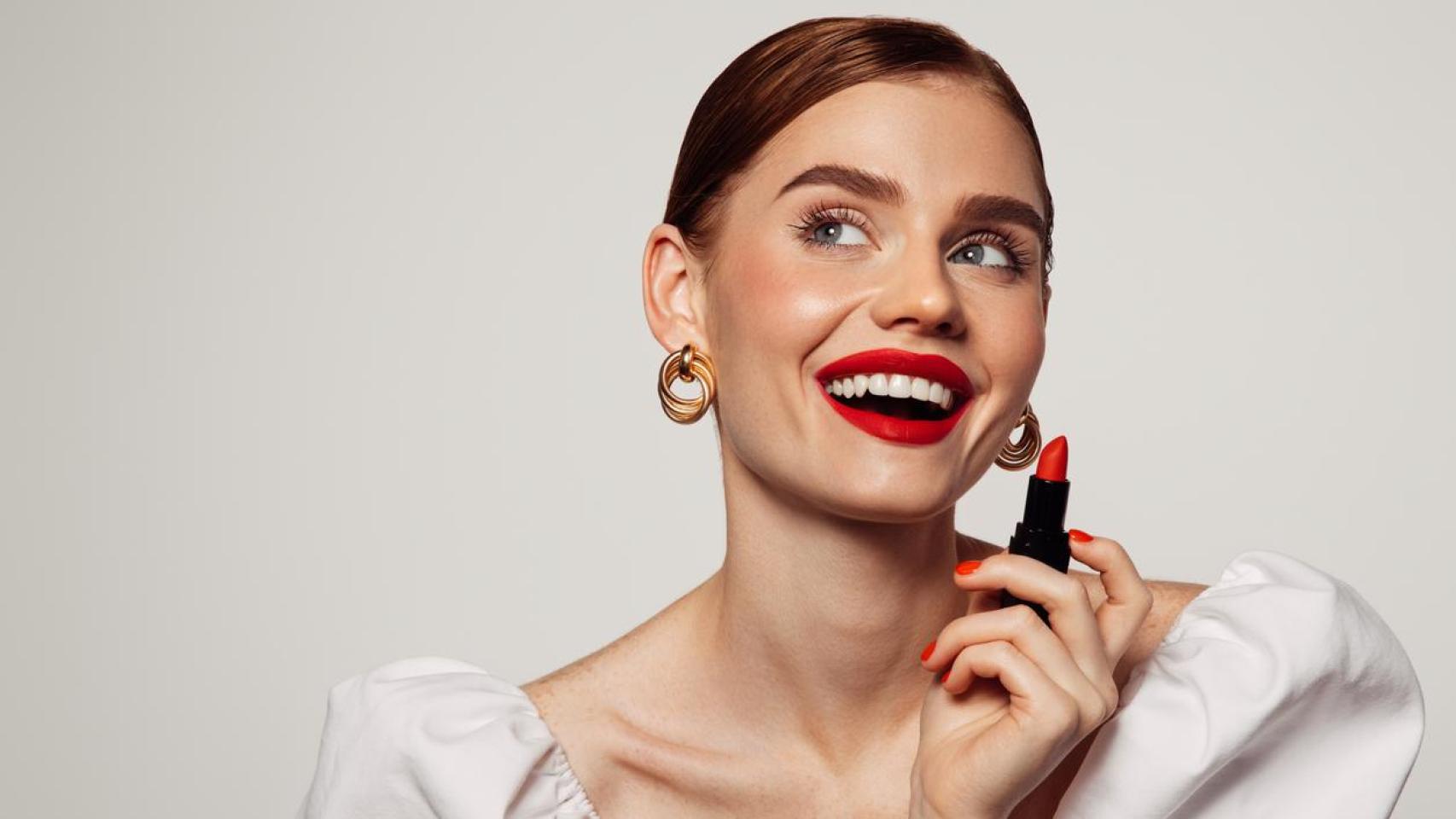 Mujer sonriente pintándose los labios.