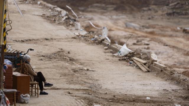 Una mujer descansa en una silla frente al barranco del Poyo en la localidad de Picanya. Efe / Kai Forsterling