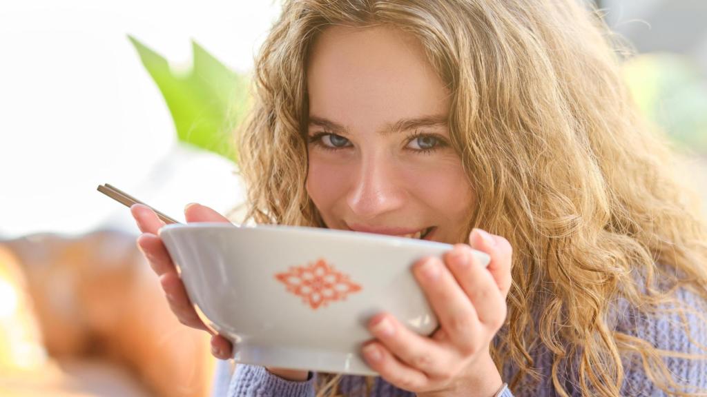 Mujer saboreando un plato de comida.