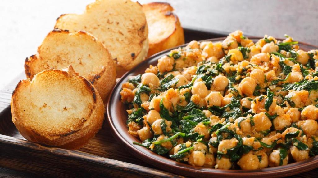 Plato de garbanzos junto a rebanadas de pan.