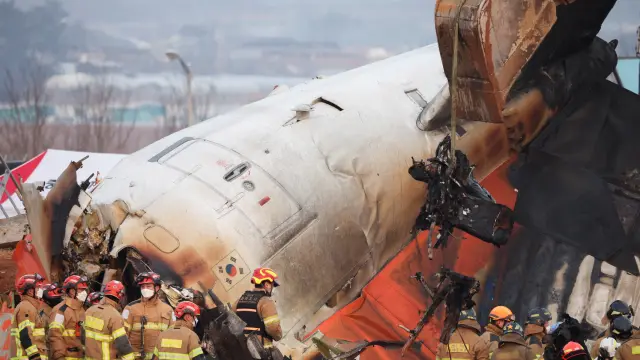 Bomberos trabajando junto a la cola del avión siniestrado en Corea del Sur