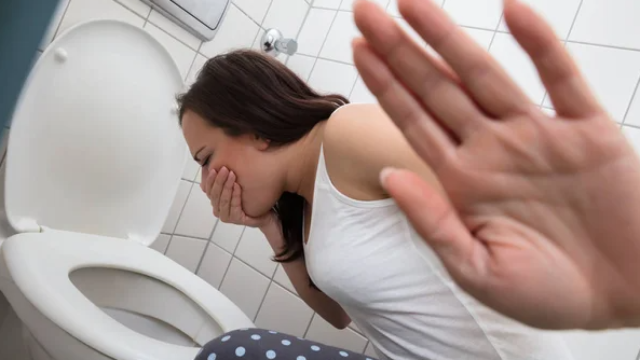 Una joven arrojando en la taza del váter.