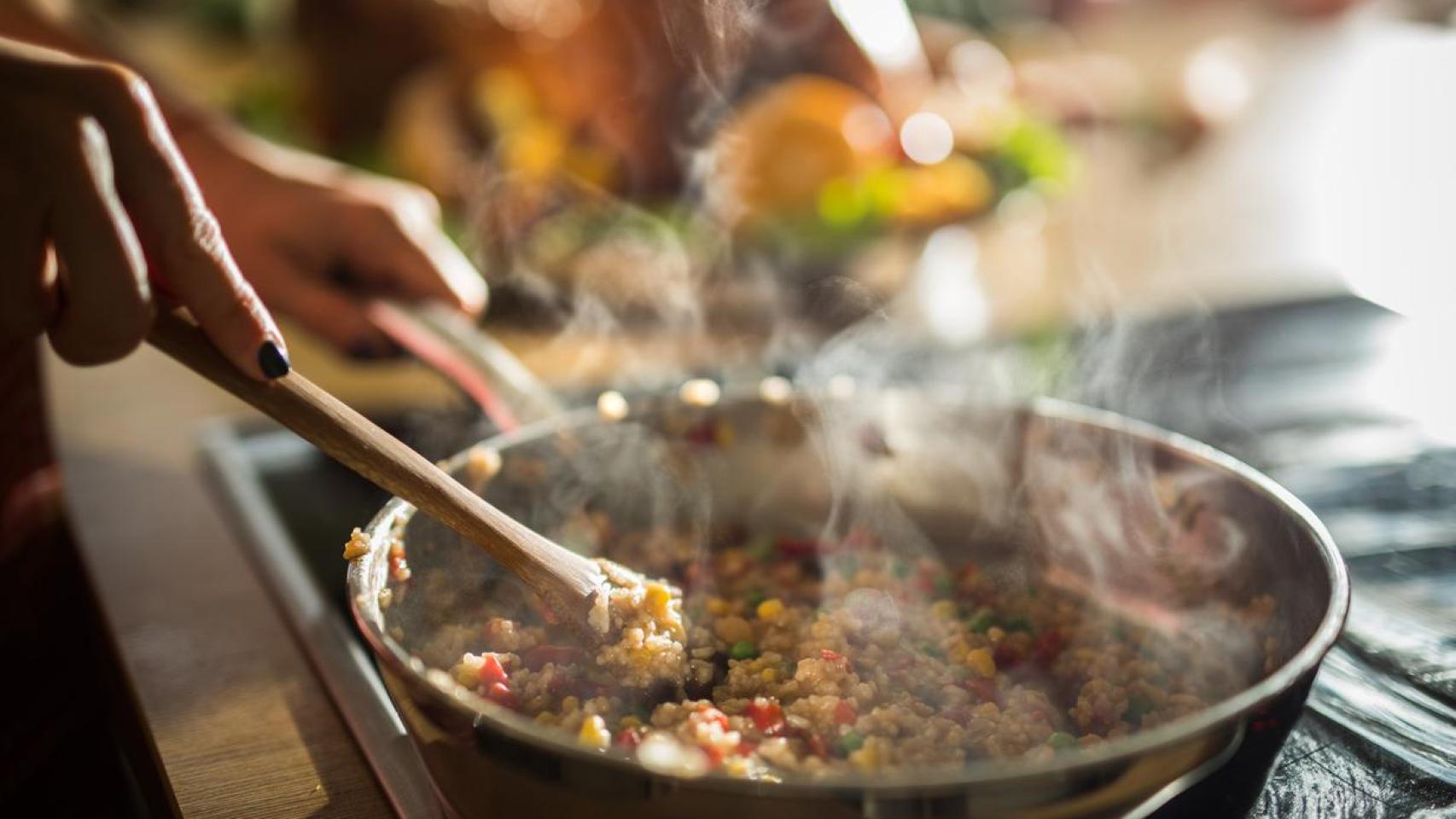 Primer plano de una mujer preparando la comida en una sartén.