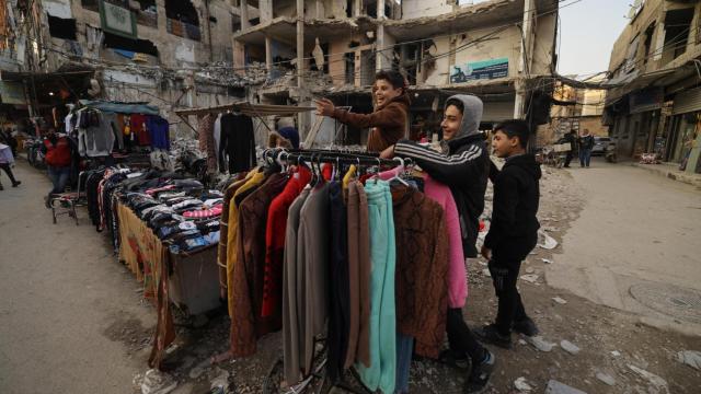 Firas, de 15 años, un vendedor ambulante, bromea con sus amigos mientras está de pie junto a su puesto en el mercado callejero, después de la derrocación del presidente Bashar al-Assad, en Douma, Siria, el 2 de enero de 2025.