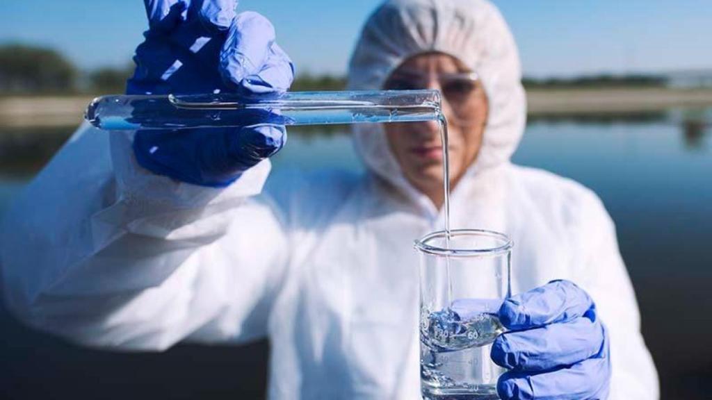 Una operaria toma una muestra de agua.