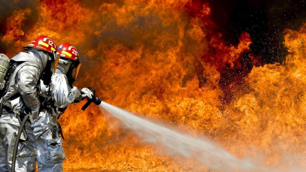 Dos bomberos apagan un incendio.