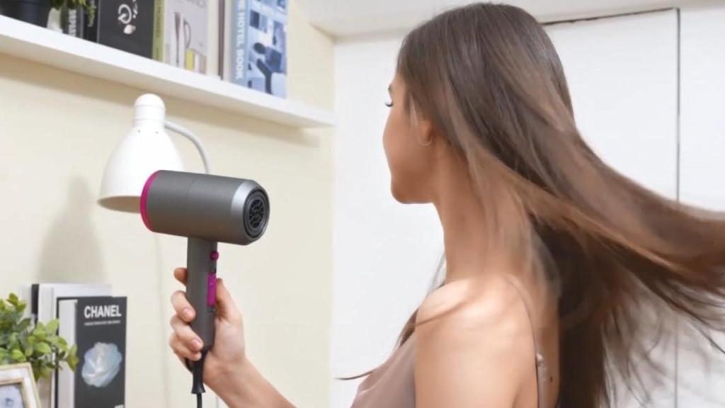 Mujer secándose el cabello con un secador iónico tipo Dyson.