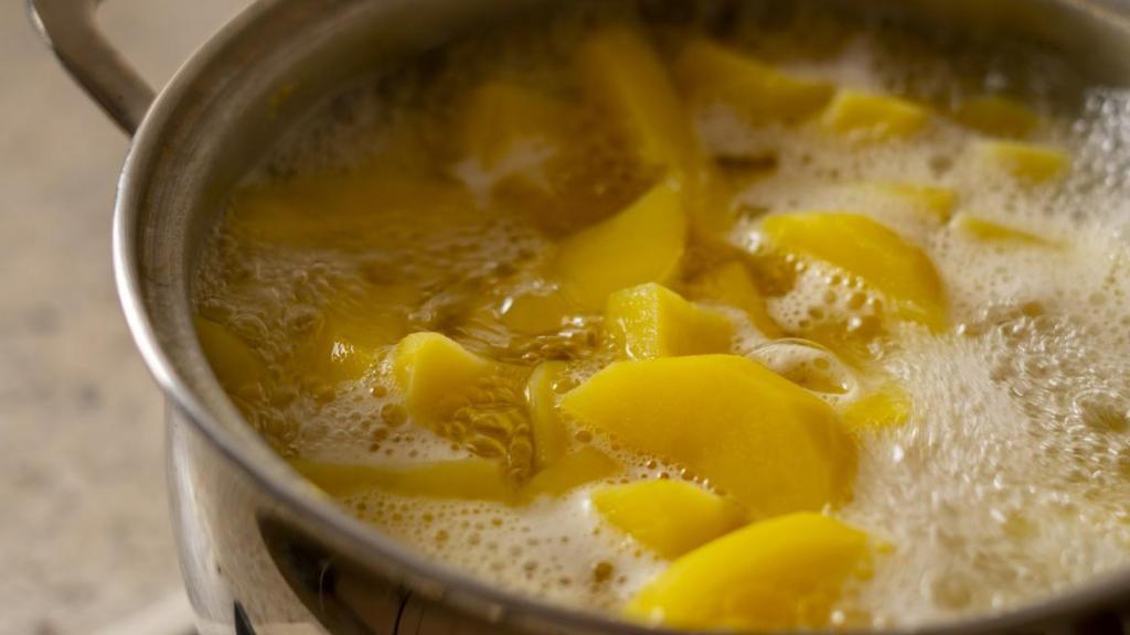 Patatas en una olla, cocinándose en agua hirviendo.