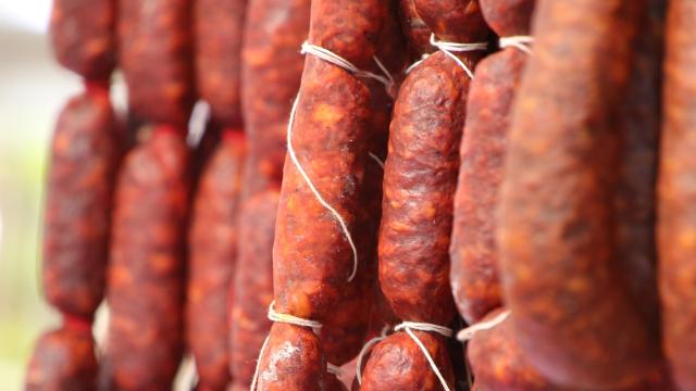 Primer plano de chorizos colgando en cuerdas.