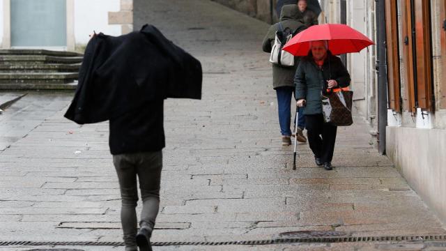 Varias personas caminando bajo la lluvia.