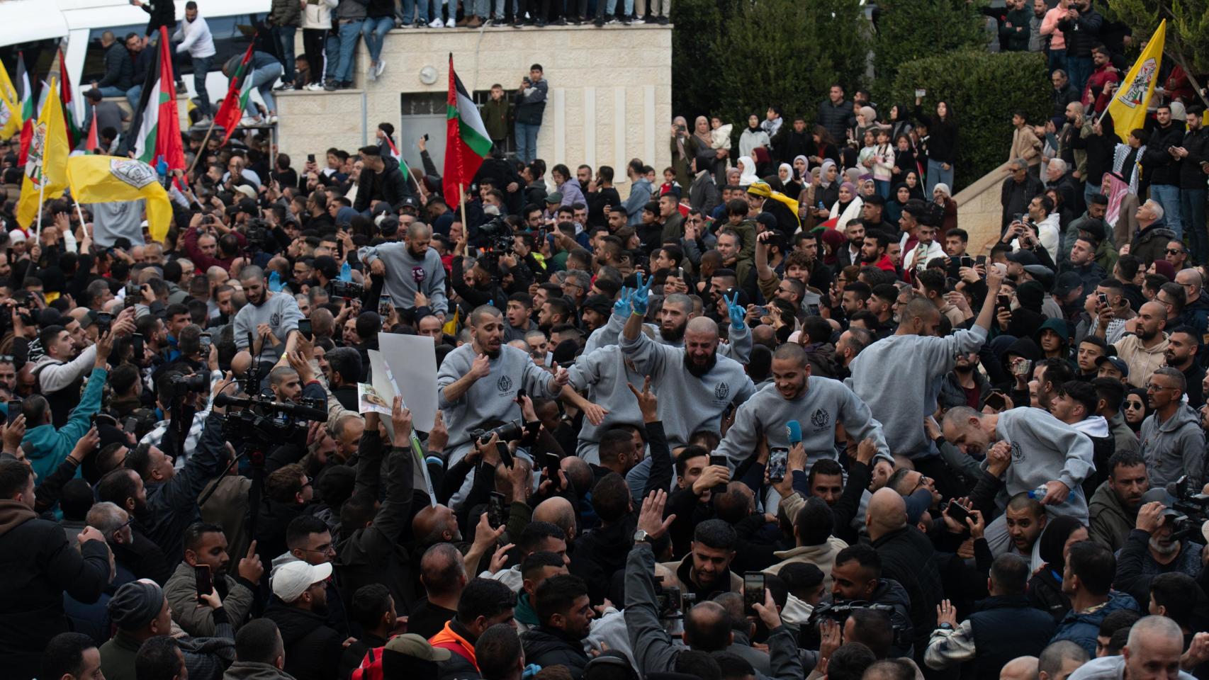 Cientos de personas y familiares reciben al centenar de presos palestinos que han sido liberados por Israel en Cisjordania, este sábado en un centro de Ramala dispuesto para su recibimiento.