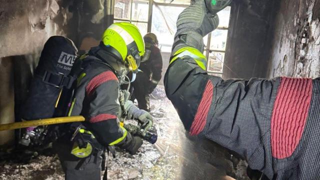 Efectivos de bomberos, en el interior de la vivienda calcinada por el fuego en Pizarra (Málaga).