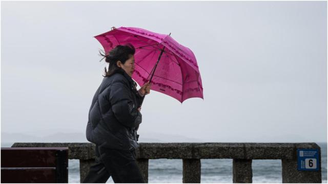 Una mujer se refugia de la lluvia con paraguas en la comarca de O Salnés, en Pontevedra