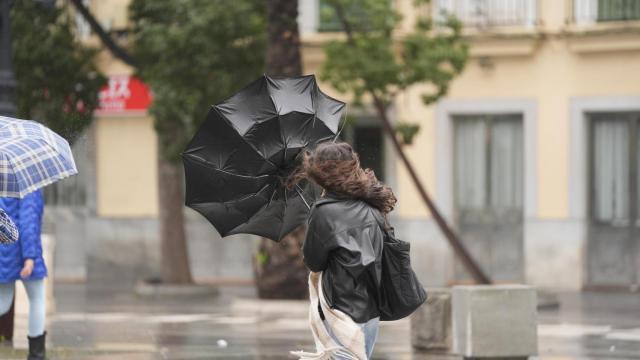 Una mujer, con problemas para llevar su paraguas, durante el paso de la borrasca Herminia por Sevilla.