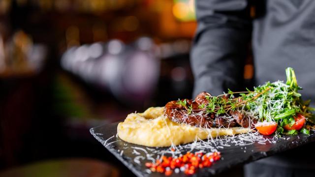 Un camarero sirve un plato de comida en un restaurante