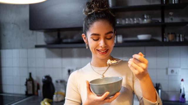 Mujer cenando en la cocina.