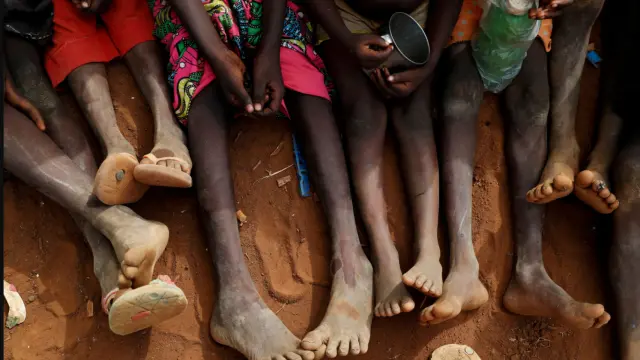 Un grupo de niñas sentadas sobre la tierra.