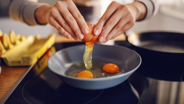 Mujer cocinando huevos en la sartén.