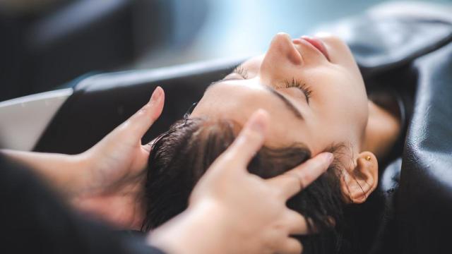 Mujer lavándose el pelo en la peluquería.