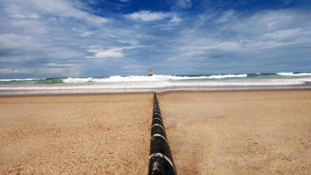 Trabajos de despliegue de un cable submarino de fibra óptica desde una playa.