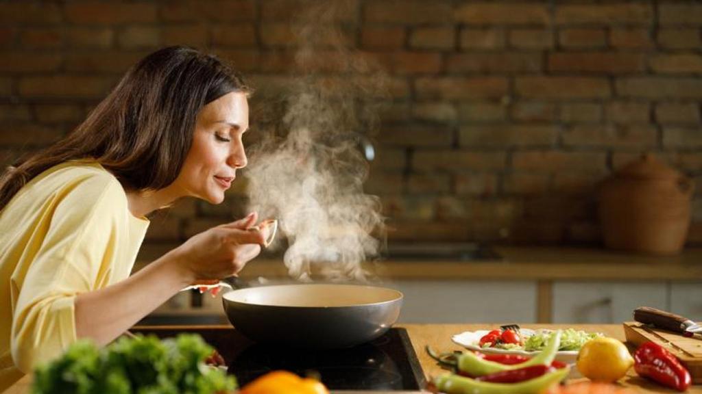 Mujer probando lo que está cocinando.