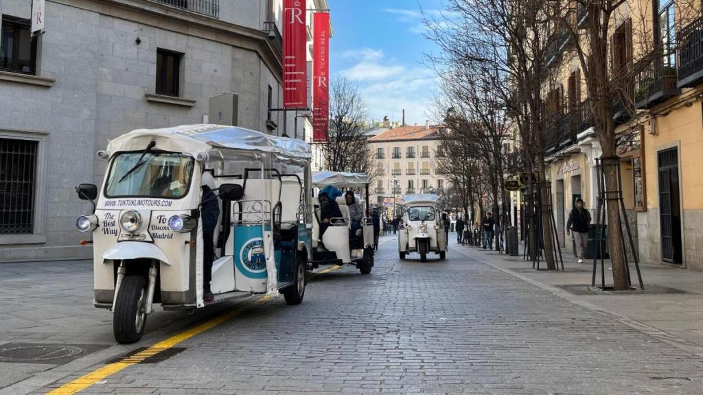 Varios tuk tuks en la calle Vergara, junto al Teatro Real y sobre una de las nuevas líneas amarillas pintadas sobre la calzada.