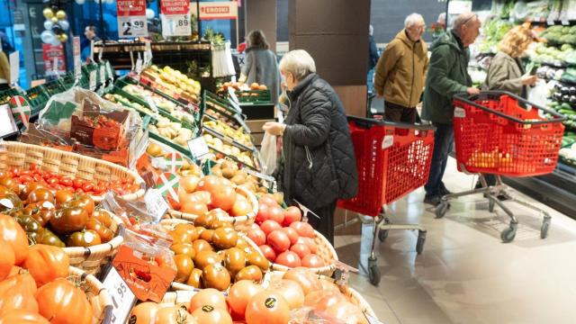 Varias personas hacen la compra en un supermercado.