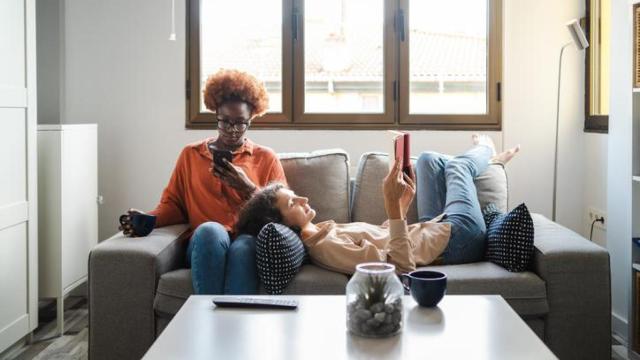 Dos mujeres en un sofá utilizando el móvil y la tablet.