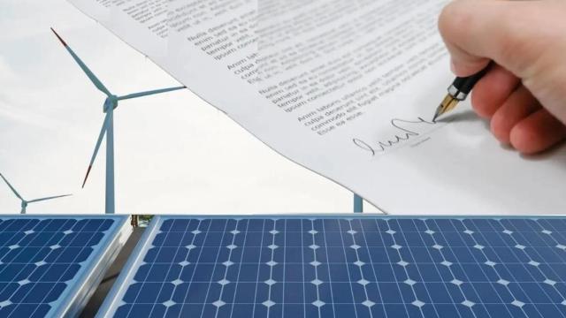 Fotomontaje de unos paneles fotovoltaicos, aerogeneradores eólicos y una firma de un documento PPA.