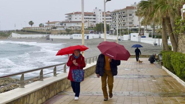 Una pareja camina por el paseo marítimo de la playa de la Torrecilla en Nerja.