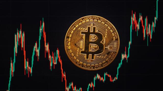 Representación física de un bitcoin sobre un gráfico de velas.