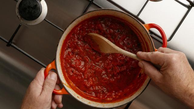 Una persona cocinando salsa de tomate (Imagen de archivo)