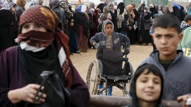 Refugiados sirios hacen fila mientras esperan paquetes de ayuda en el campo de refugiados de Al Zaatari, en la ciudad jordana de Mafraq, cerca de la frontera con Siria.