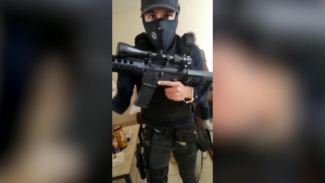 Uno de los presuntos estafadores sosteniendo un arma de fuego durante un vídeo de extorsión a las víctimas.