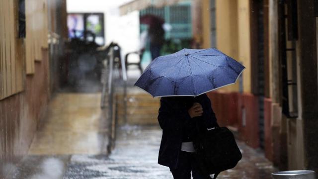 Imagen de archivo de una persona protegiéndose de la lluvia con un paraguas.