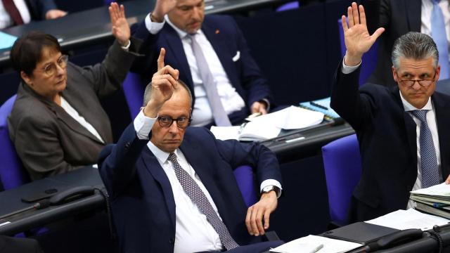 El canciller alemán, Friedrich Merz (i), alza la mano durante la votación en el Bundestag.