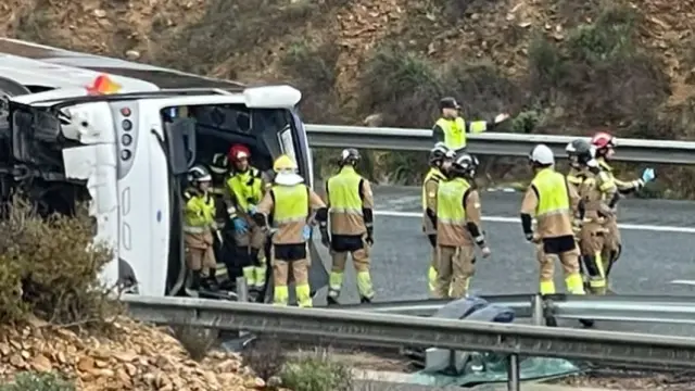 El autobús volcado en la Autovía del Mediterráneo (A-7), en el carril de circulación en sentido Alicante, inspeccionado por los bomberos del SEIS de Murcia.