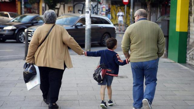 Dos jubilados pasean a su nieto.