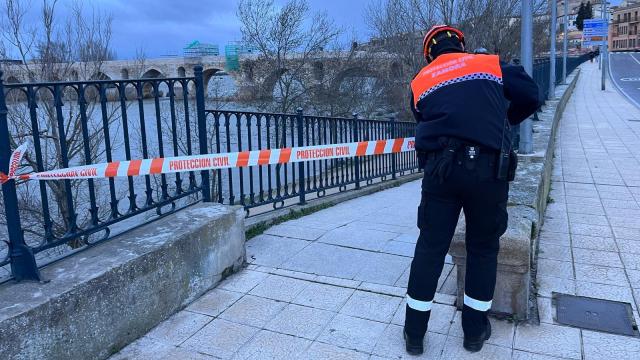 Una persona de Protección Civil acordonando los acceso al río Duero a su paso por Zamora