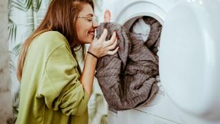 Una mujer tendiendo la colada en casa después de lavar la ropa.