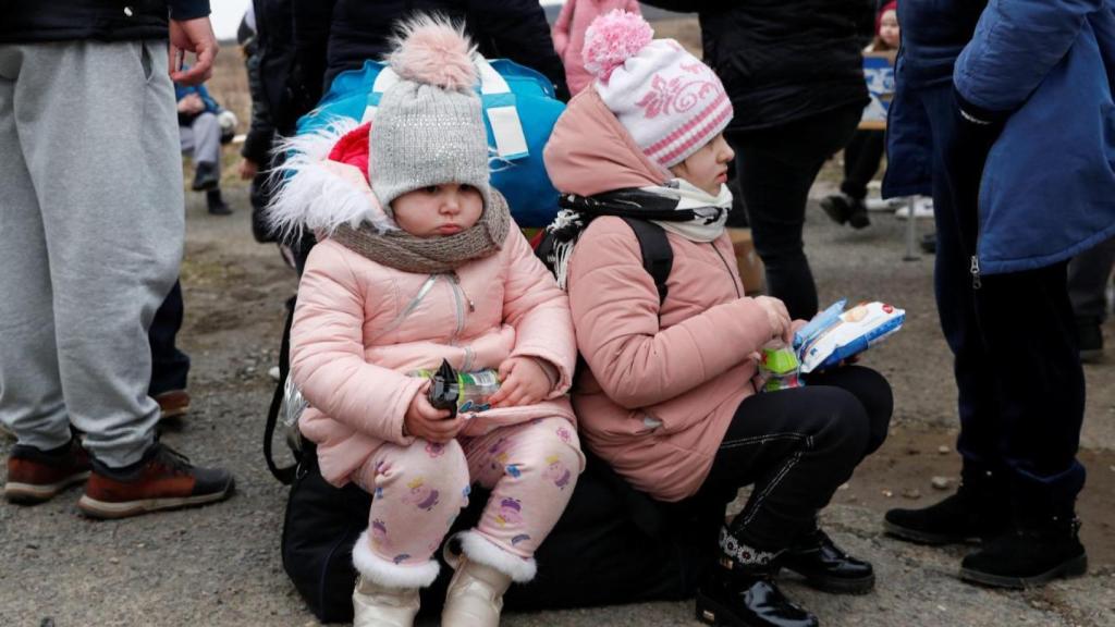 Niños que huyen de Ucrania se sientan en su equipaje a su llegada a Hungría, después de que Rusia lanzara una operación militar masiva contra Ucrania, en un cruce fronterizo en Beregsurany, Hungría, el 26 de febrero de 2022.